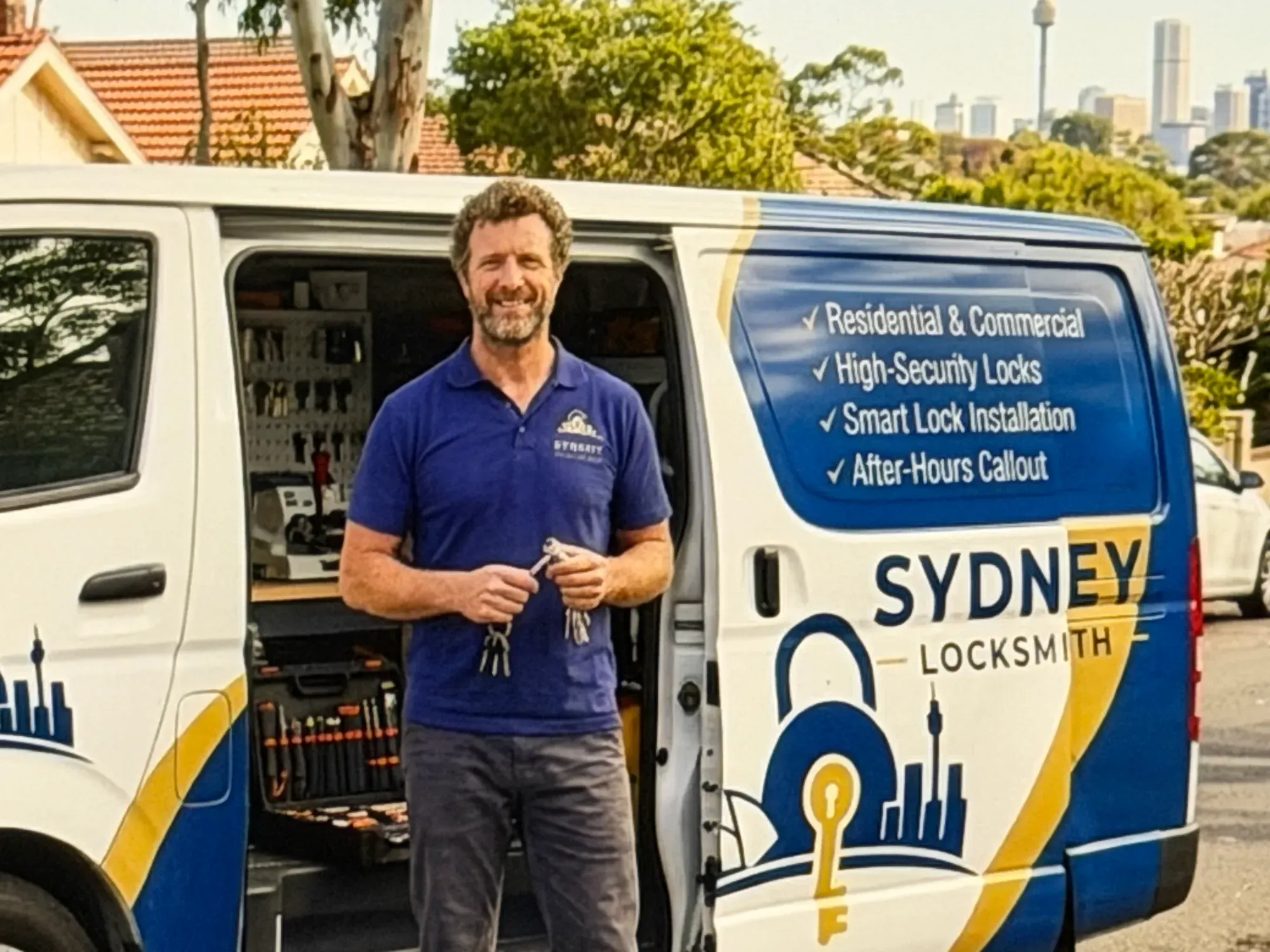 Sydney Locksmith technician holding your new keys beside his fully stocked service van